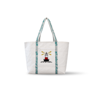 The front of a large tote made of white reclaimed sailcloth. The straps are made of sail tie webbing and are white with aqua blue lettering that reads "Island House". A lighthouse is embroidered on the middle of the front.