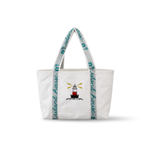 The front of a medium tote made of white reclaimed sailcloth. The straps are made of sail tie webbing and are white with aqua blue lettering that reads "Island House". A lighthouse is embroidered on the middle of the front.