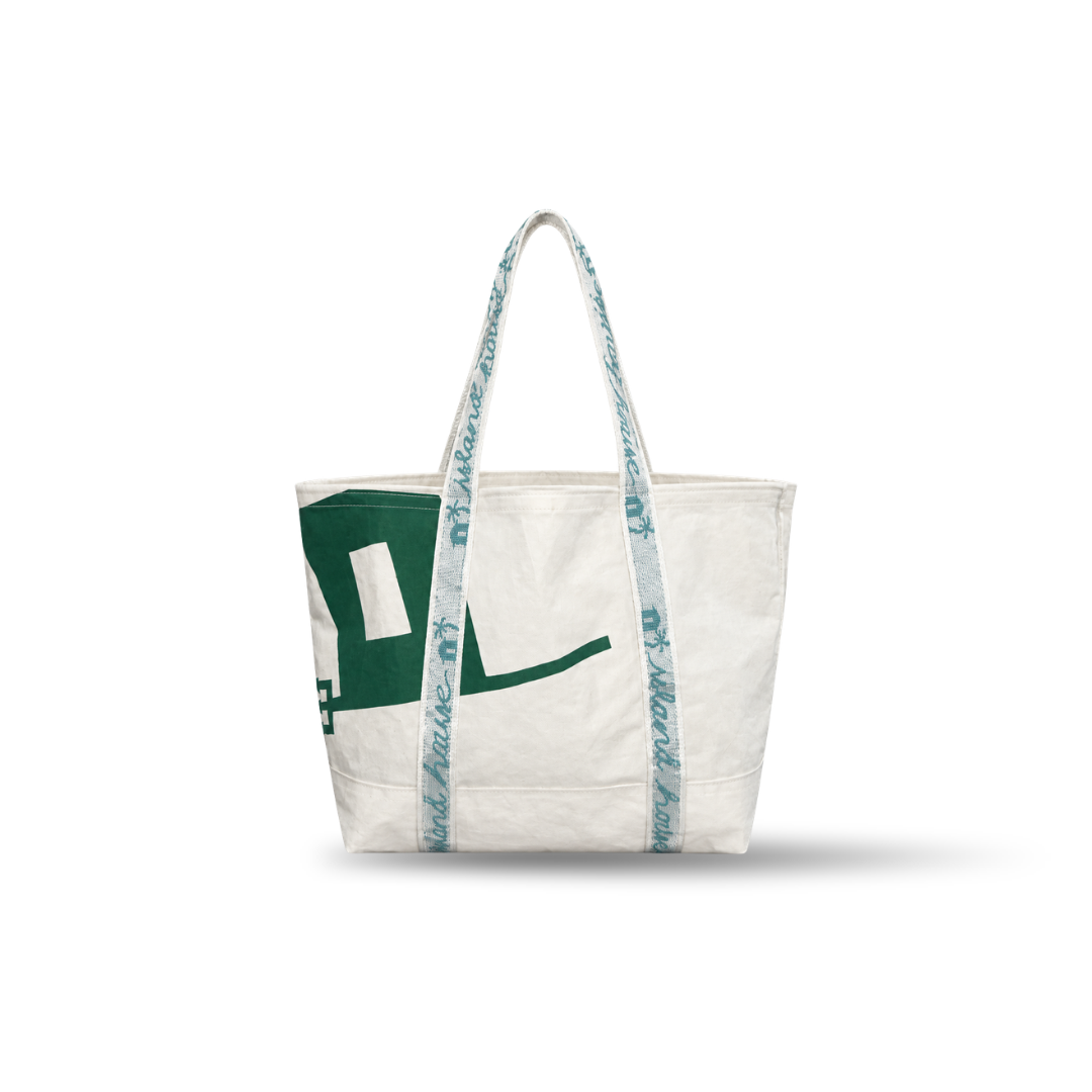 The front of a large tote made of white reclaimed sailcloth. The straps are made of sail tie webbing and are white with aqua blue lettering that reads "Island House". The sailcloth features original green markings.