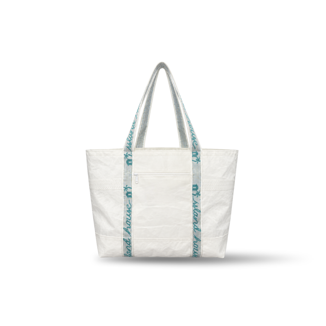 The front of a large tote made of plain white reclaimed sailcloth. The straps are made of sail tie webbing and are white with aqua blue lettering that reads "Island House".